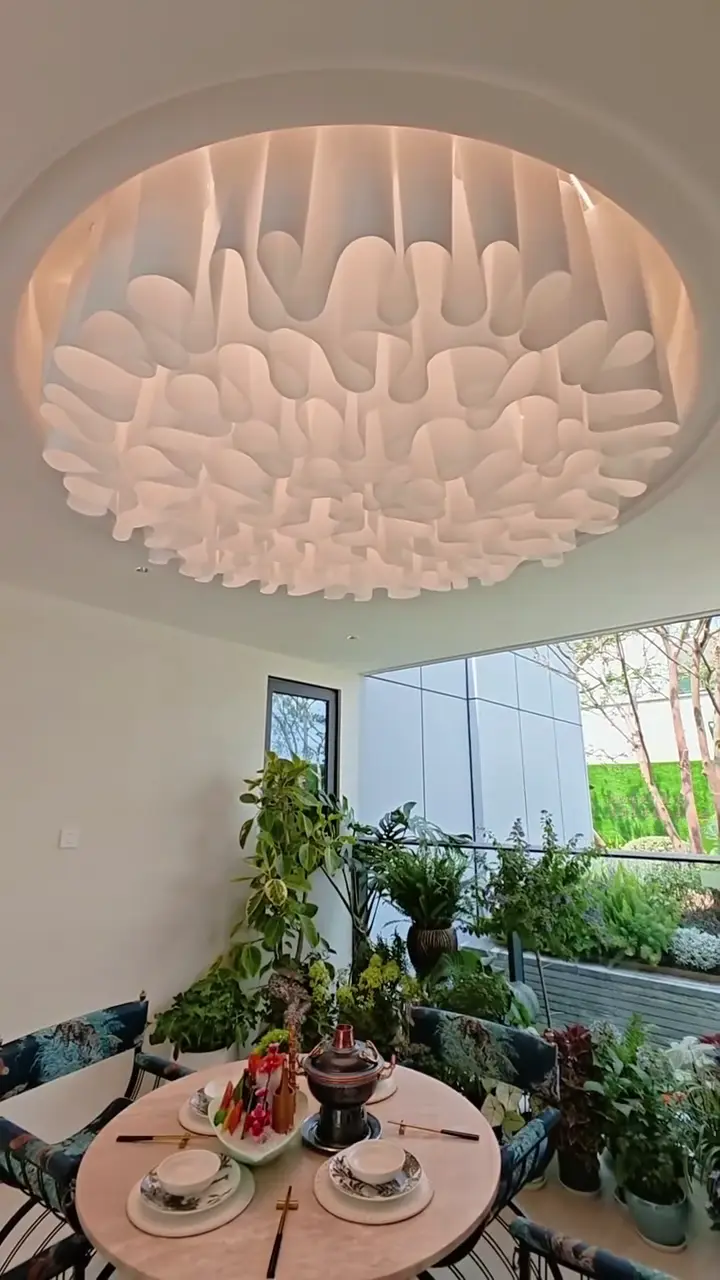 Sculptural fabric ceiling arranged as a circular cloud-like feature above a dining table